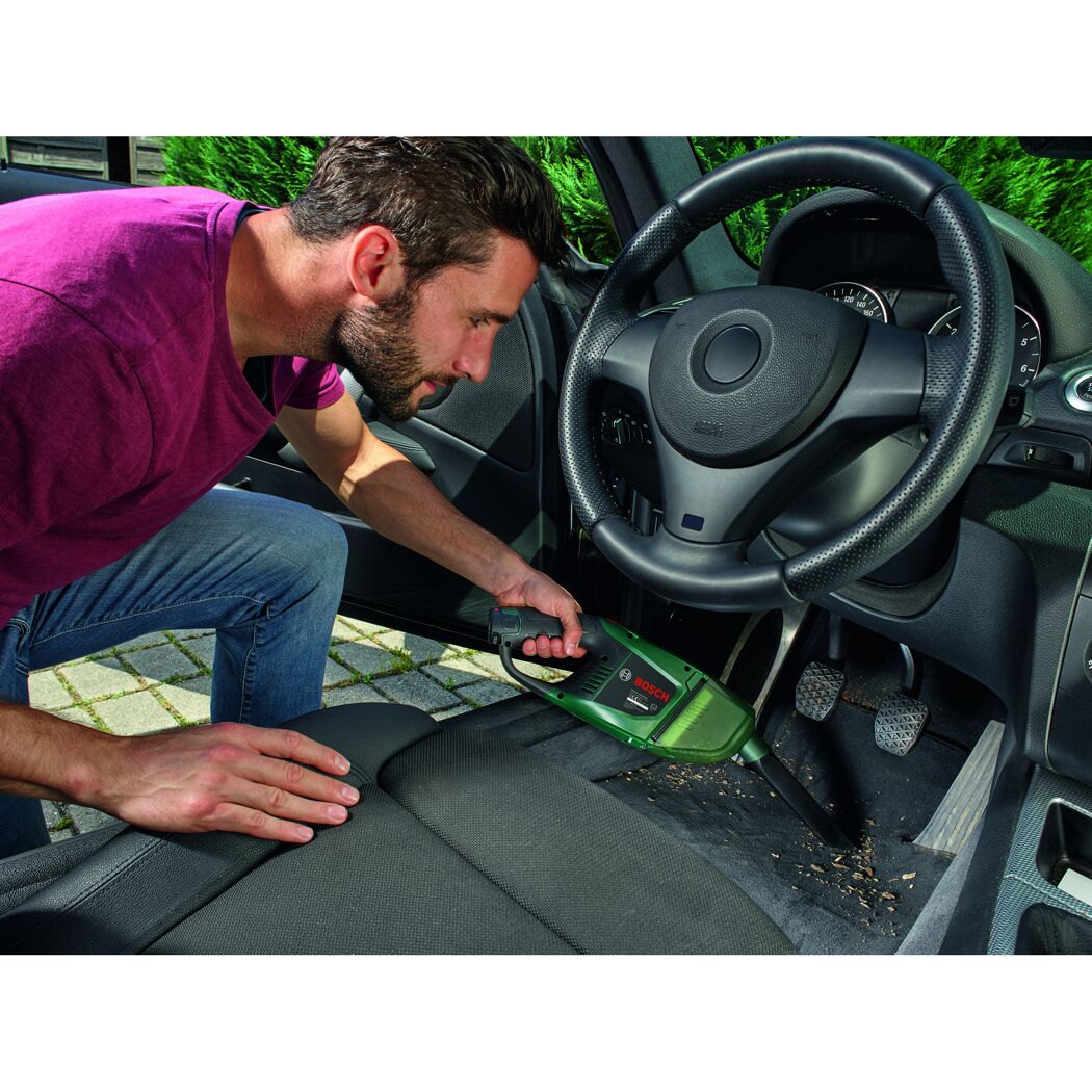 Person saugt mit einem Bosch EasyVac 12 Akku-Handstaubsauger den Autositz ab.