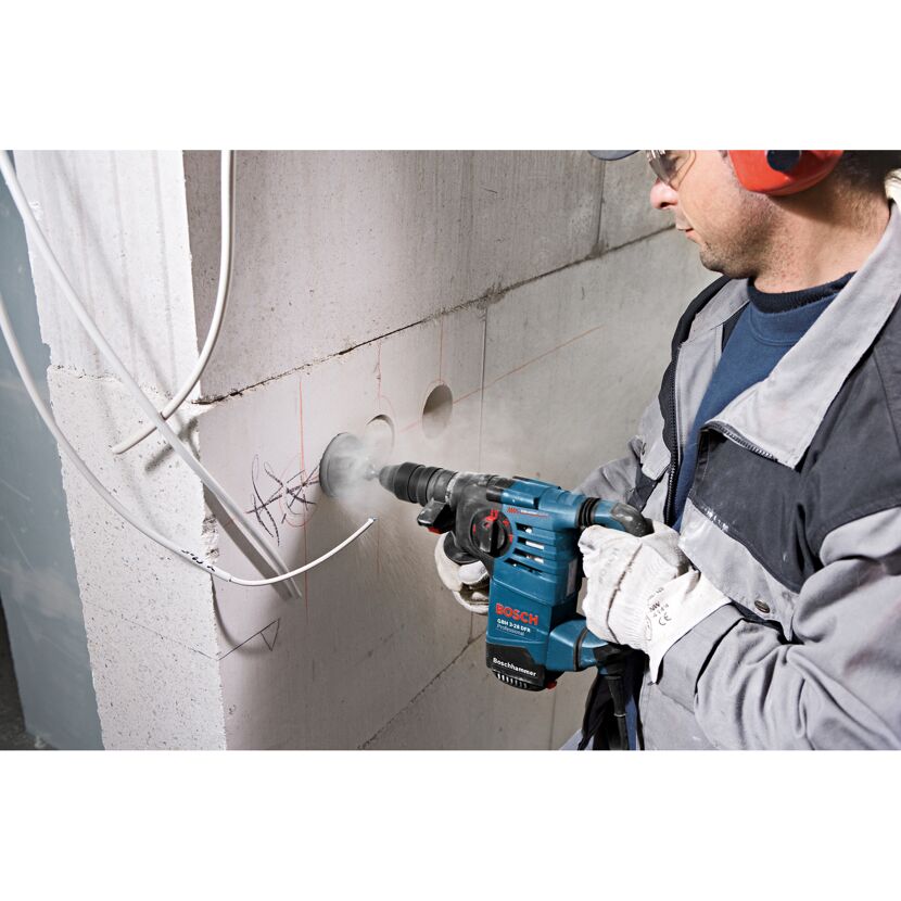 Person bohrt mit Bohrhammer ein Loch in eine Wand.