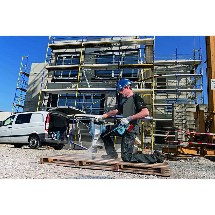 Person verwendet einen Bohrhammer und ein Gebläse auf einer Baustelle.