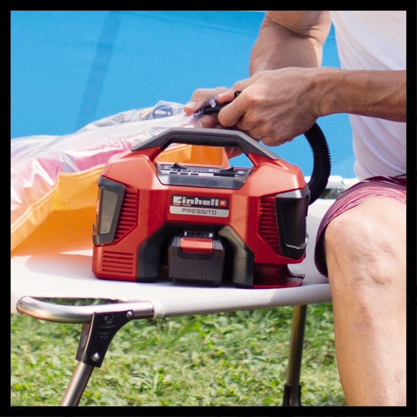 Person pumpt Luftmatratze mit Akku-Kompressor Pressito von Einhell auf.