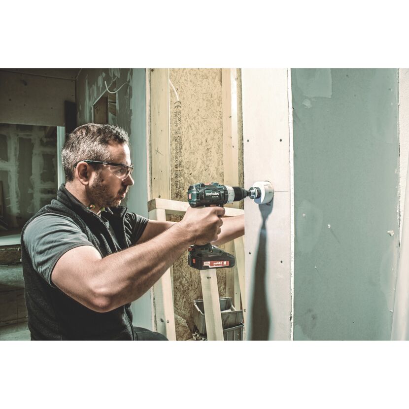 Person bohrt mit einem Akku-Bohrschrauber in eine Wand.