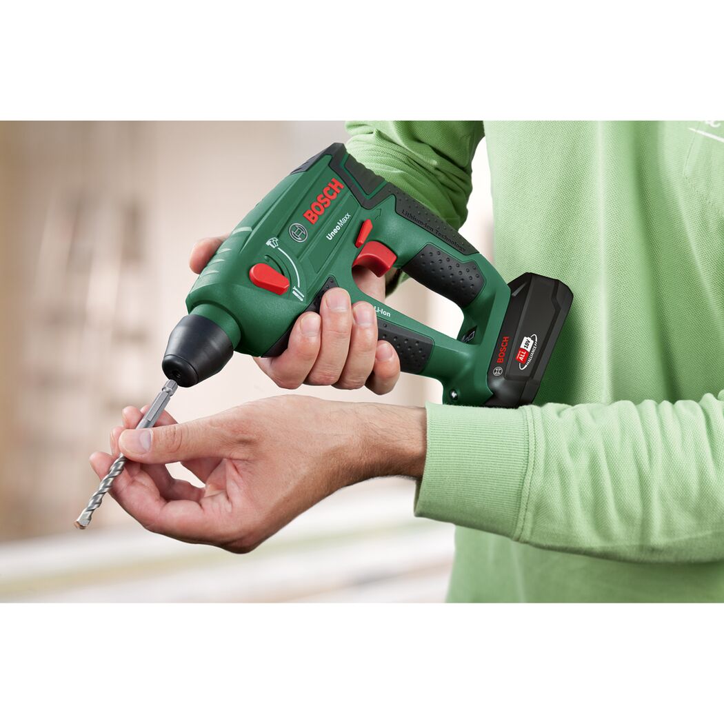 Person hält einen Bosch Akku-Bohrhammer Uneo Maxx und einen Bohrer.