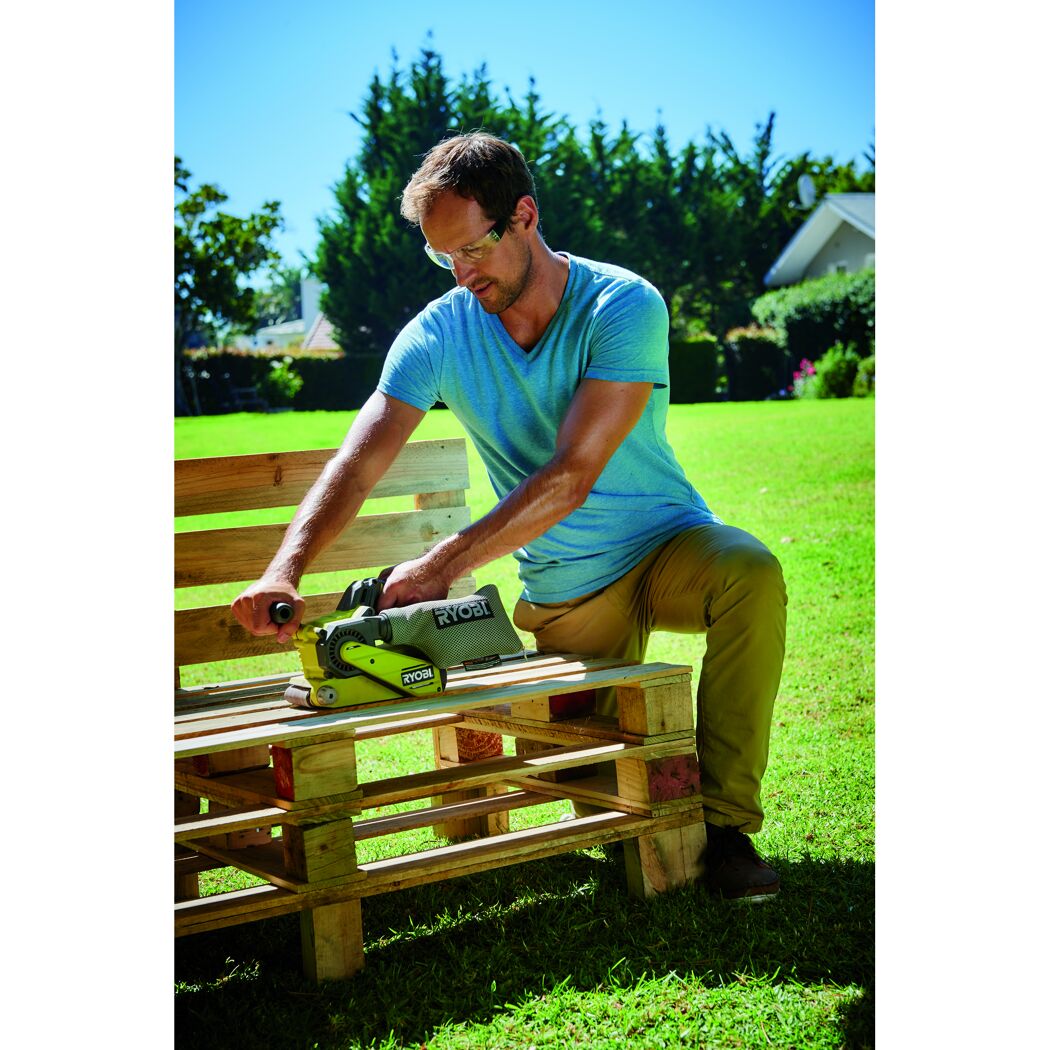 Person schleift Holz mit RYOBI Bandschleifer