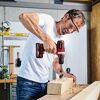 Person bohrt mit einem Akkuschrauber in ein Holzstück.