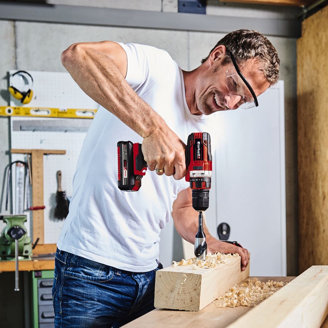 Person bohrt mit einem Akkuschrauber in ein Holzstück.