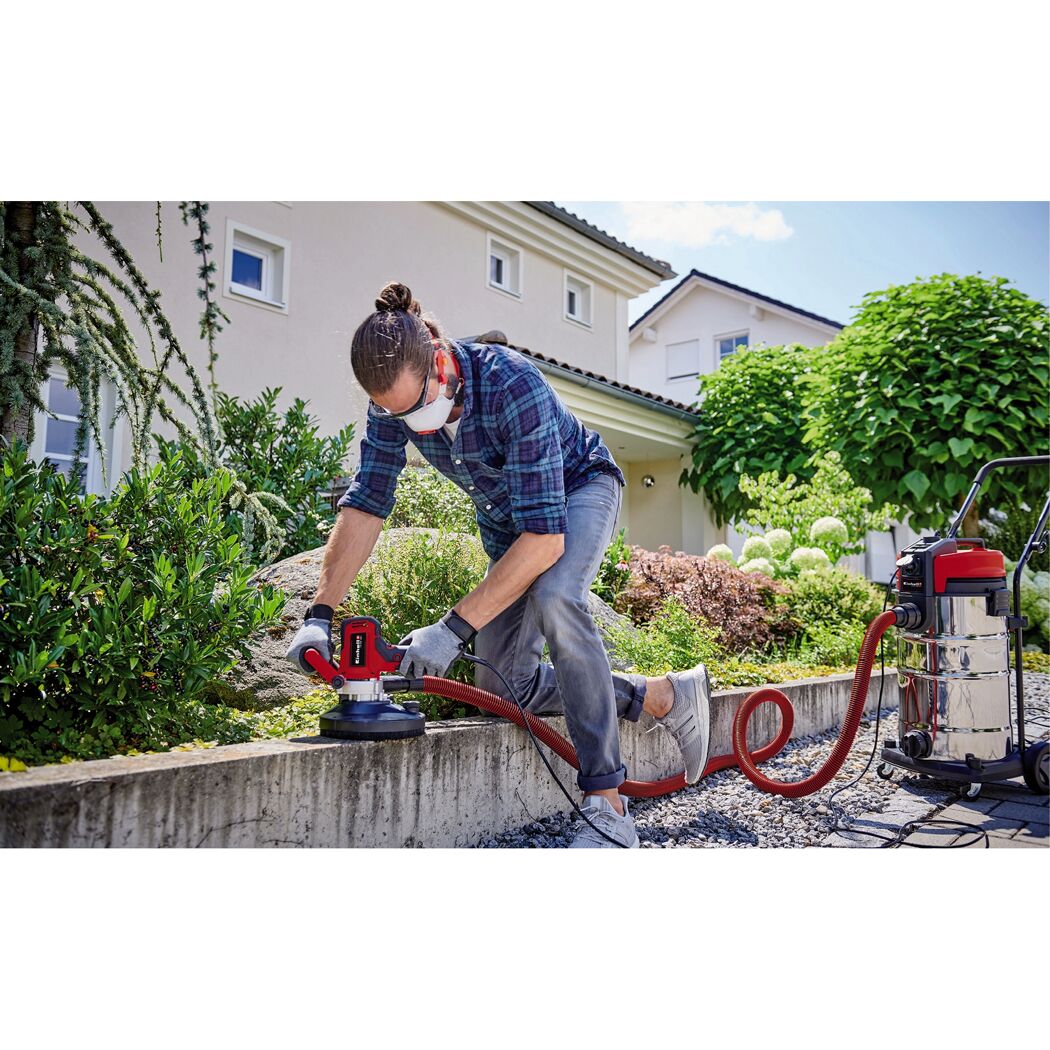 Person schleift eine Mauer mit einem Einhell-Wandschleifer.