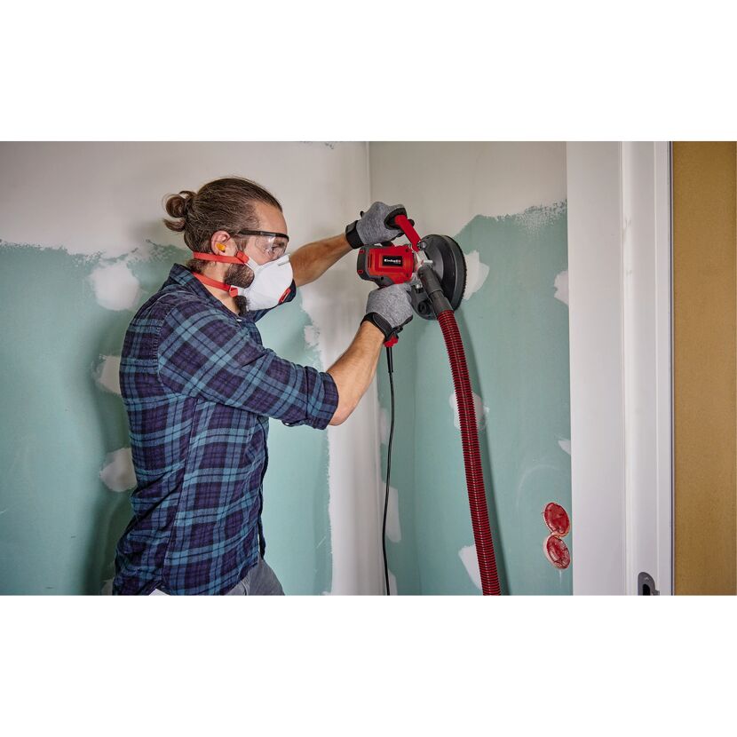 Person schleift Wand mit Einhell-Schleifer.
