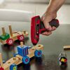 Person klebt mit Heißklebepistole Holzspielzeug.