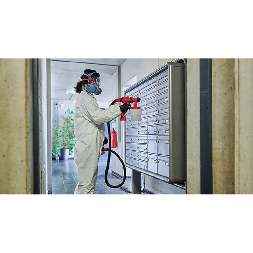 Person in Schutzkleidung desinfiziert Briefkästen mit Sprühgerät