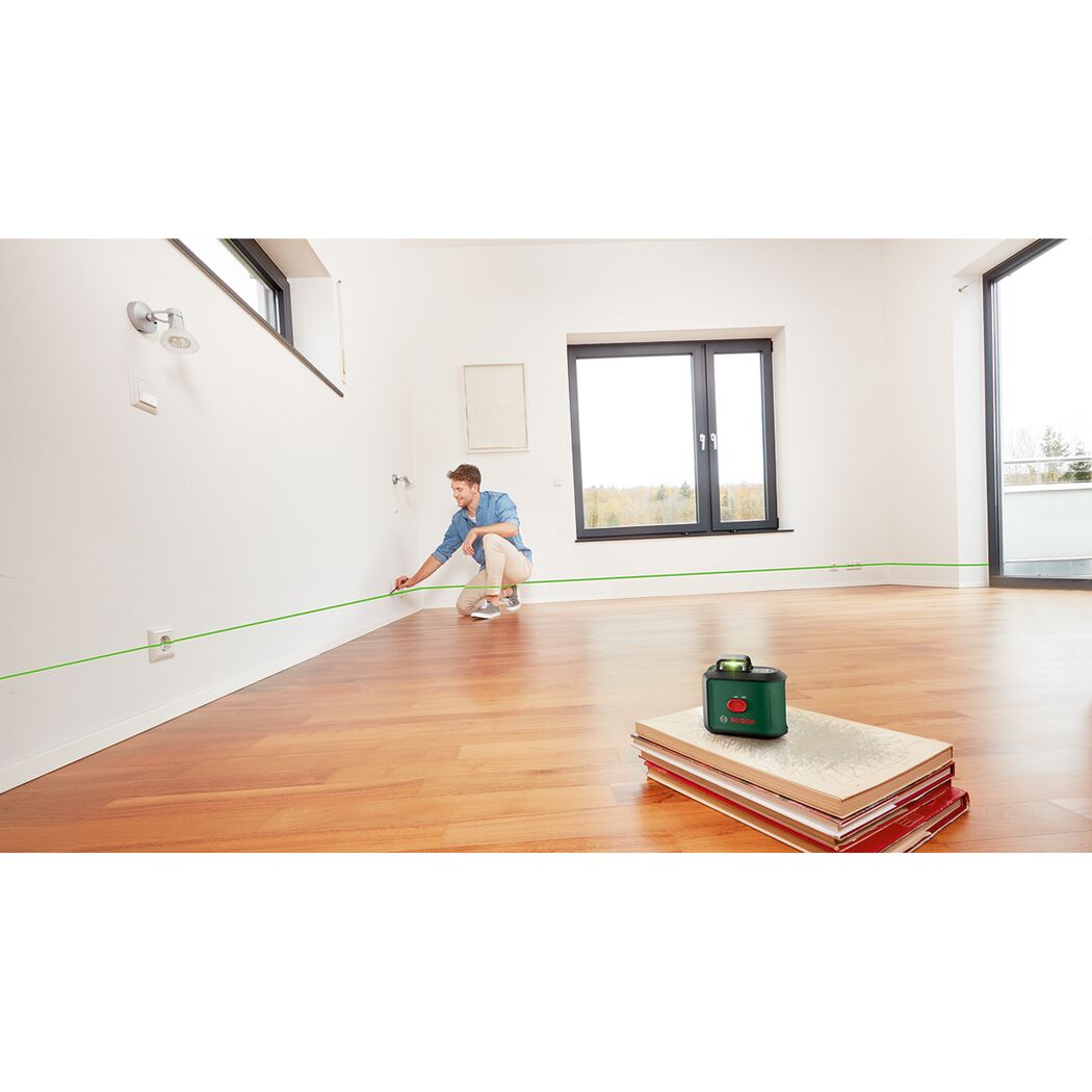 Person markiert eine Linie mit einem Kreuzlinienlaser an der Wand.