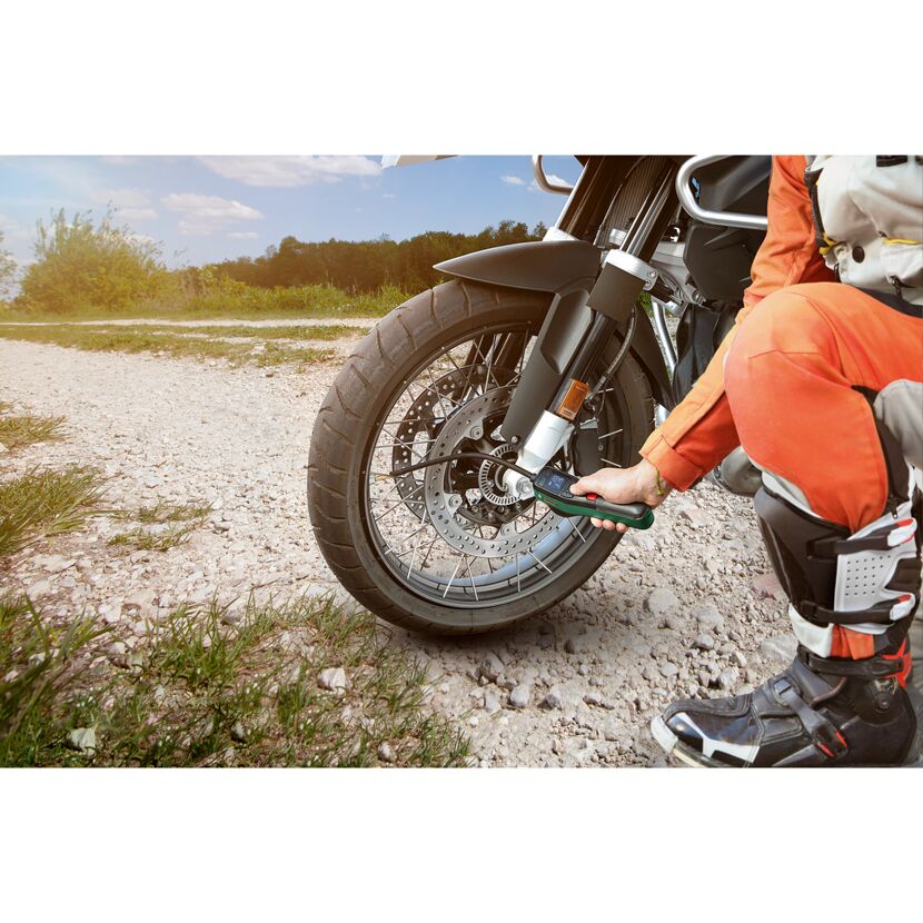 Person prüft mit Druckluftpumpe den Reifendruck am Motorrad
