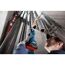 Person schleift mit Geradschleifer ein Rohr.