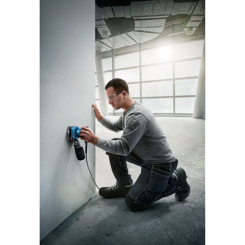 Person schleift Wand mit Schleifer