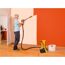 Person streicht eine Wand mit einem Farbsprühsystem orange.
