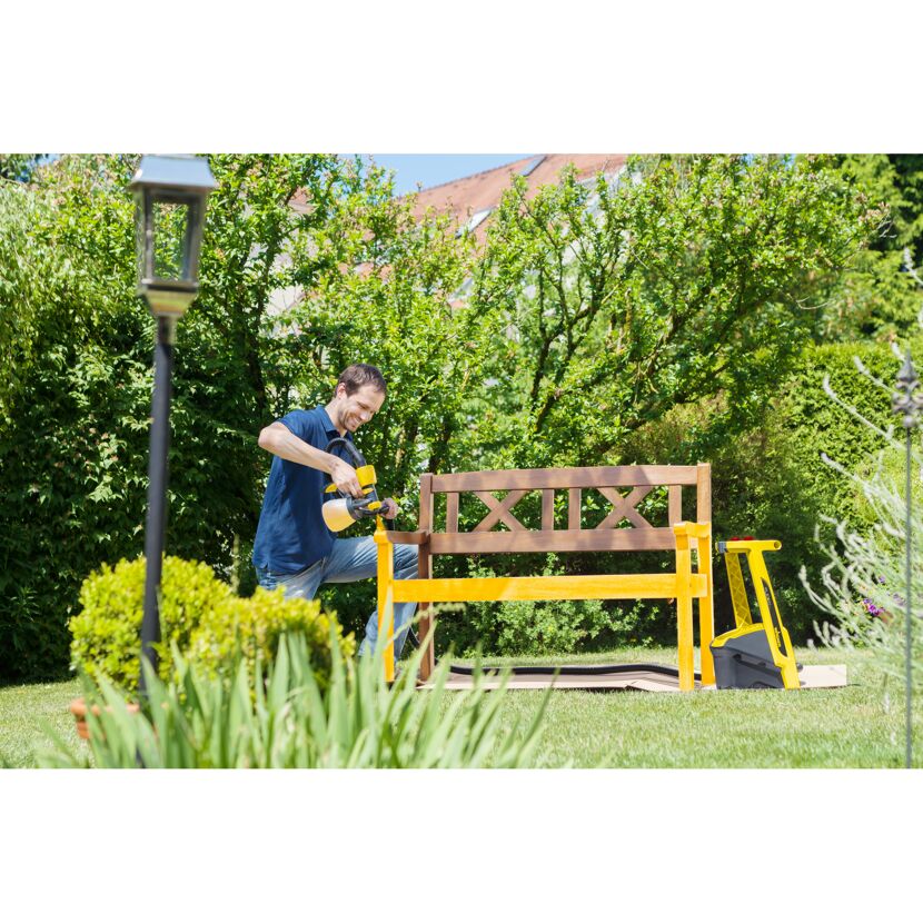 Person streicht Gartenbank mit Farbsprühsystem