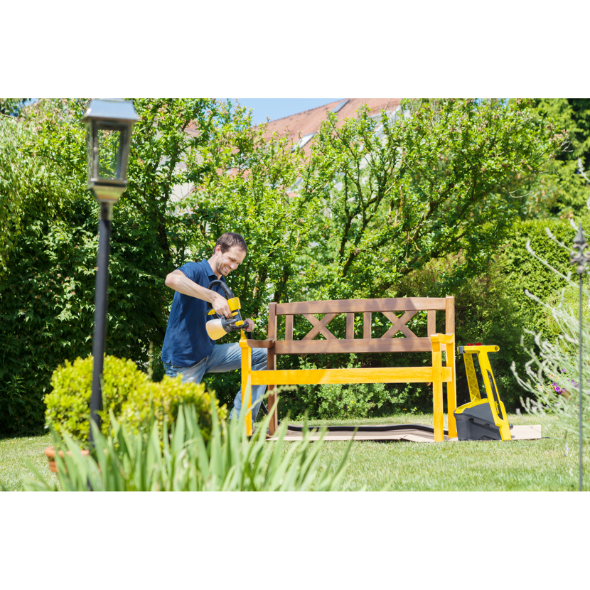 Person streicht Gartenbank mit Farbsprühsystem
