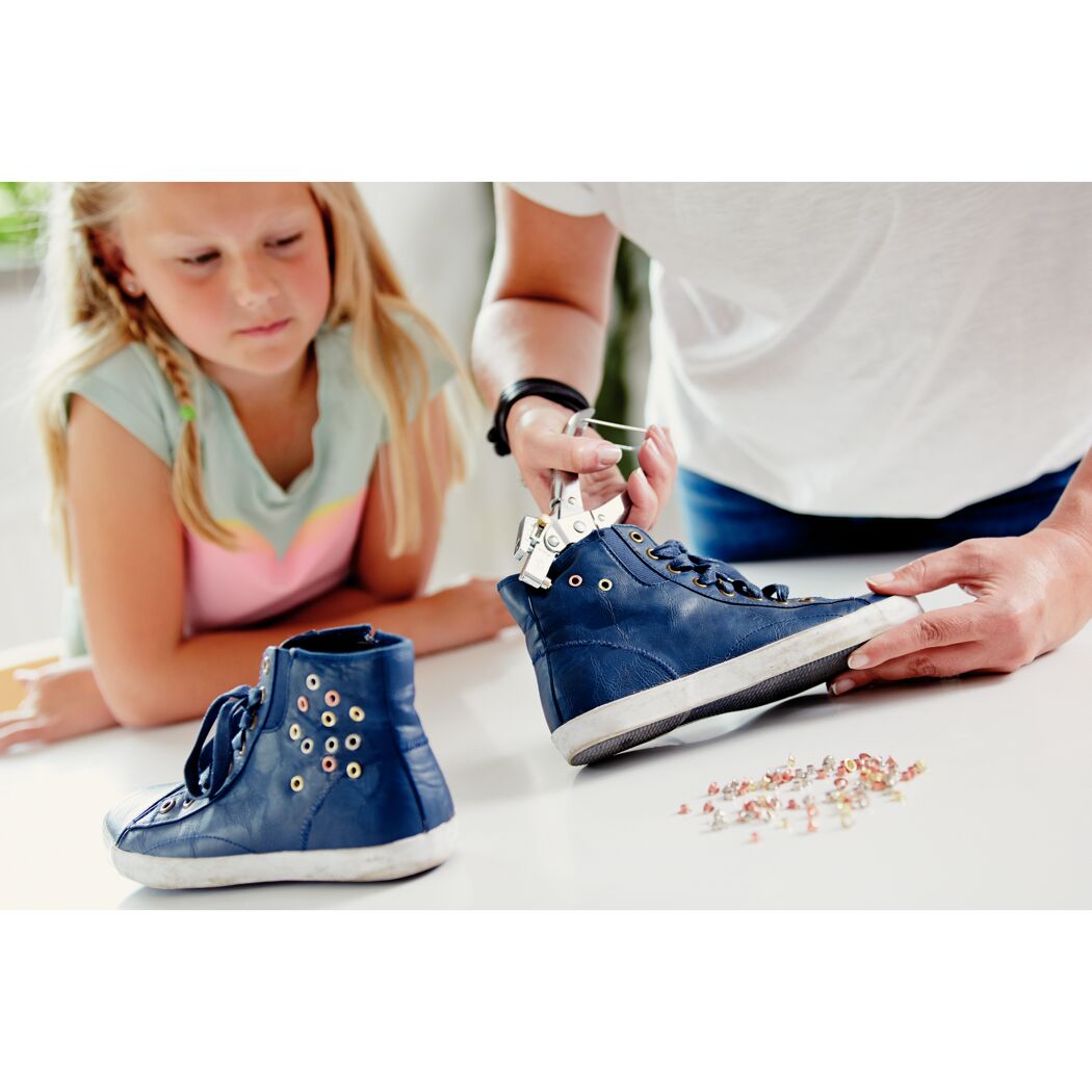 Person verwendet eine Ösenzange zum Anbringen von Ösen an einem Schuh.