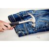 Person befestigt eine Hohlniete mit einem Hammer an einer Jeans