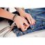 Person befestigt Druckknopf mit einer Druckknopfzange an Jeans.