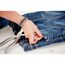 Person befestigt mit einer Zange eine Hohlniete an einer Jeans.