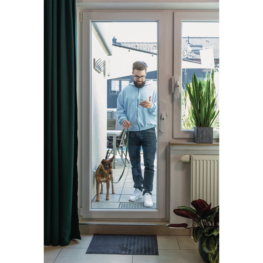 Person mit Hund und Smartphone an der Terrassentür