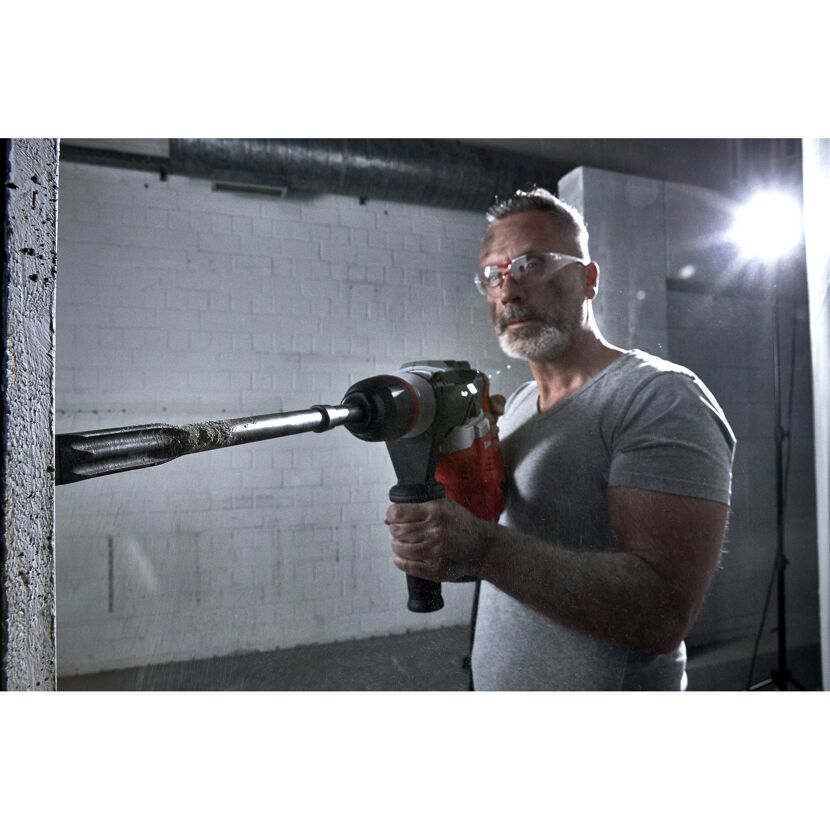 Person mit Meißel und Bohrhammer an einer Betonwand