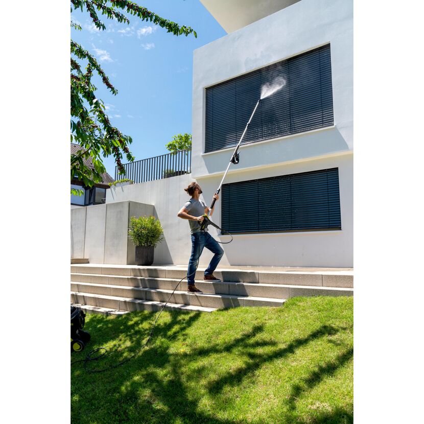 Person reinigt Hausfassade mit Hochdruckreiniger und Teleskopstrahlrohr.