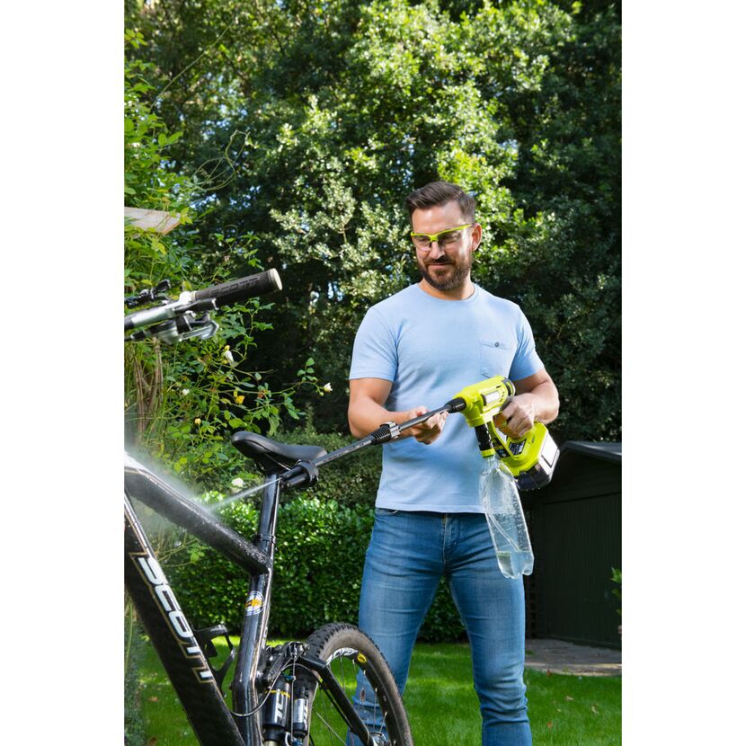 Person reinigt Fahrrad mit Hochdruckreiniger