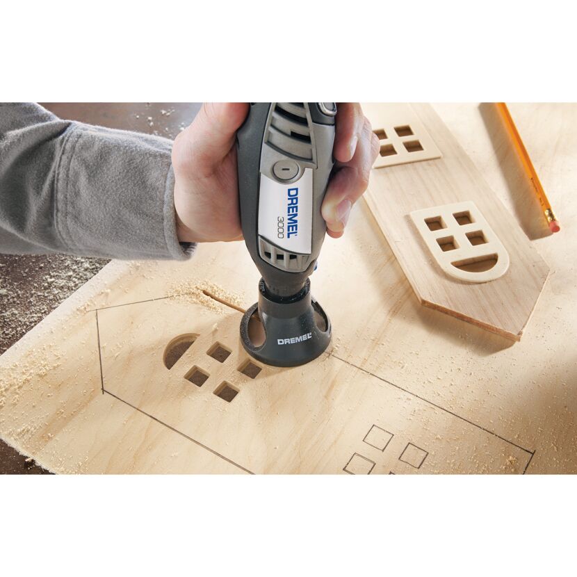 Person fräst mit Dremel 3000 ein Fenster in Holz.