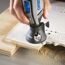 Person fräst mit Dremel Fräsaufsatz ein Muster in Holz