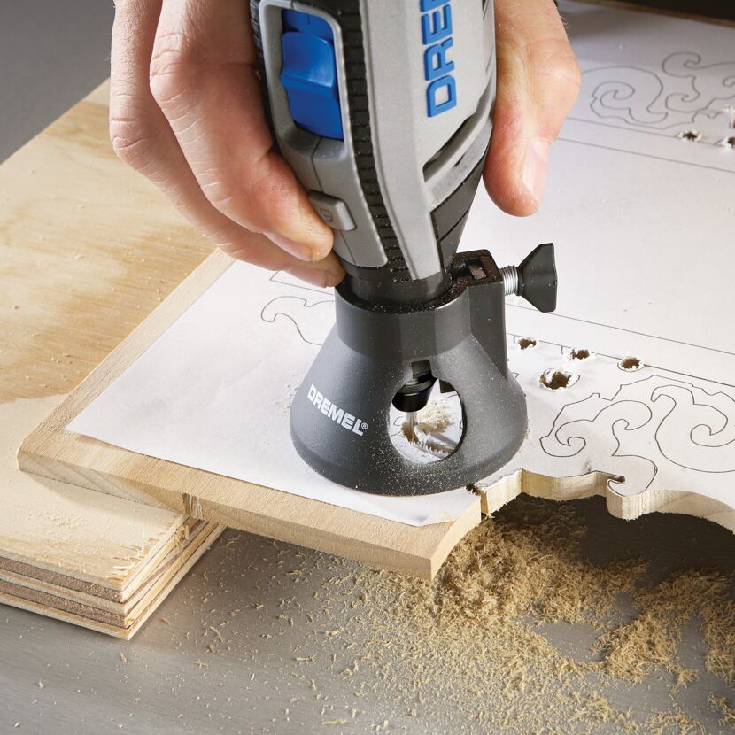 Person fräst mit Dremel Fräsaufsatz ein Muster in Holz