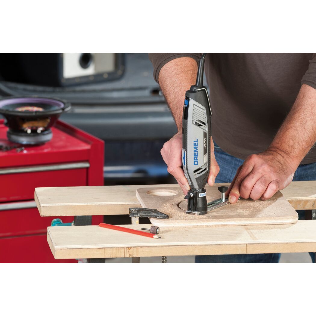 Person fräst mit einem Dremel 4300 ein Loch in ein Holzbrett.