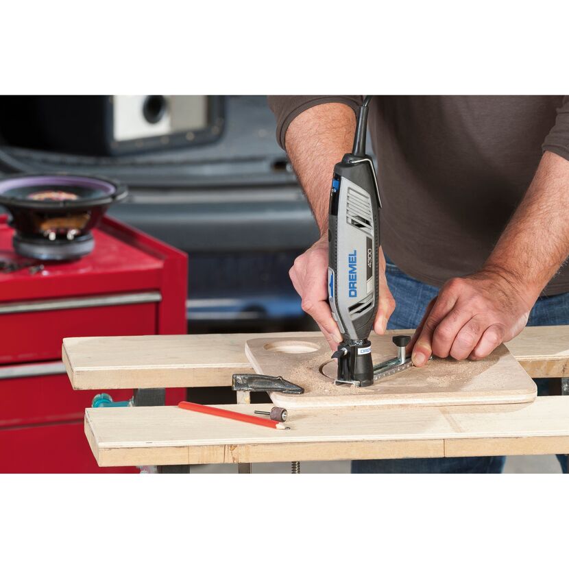 Person fräst mit einem Dremel 4300 ein Loch in ein Holzbrett.