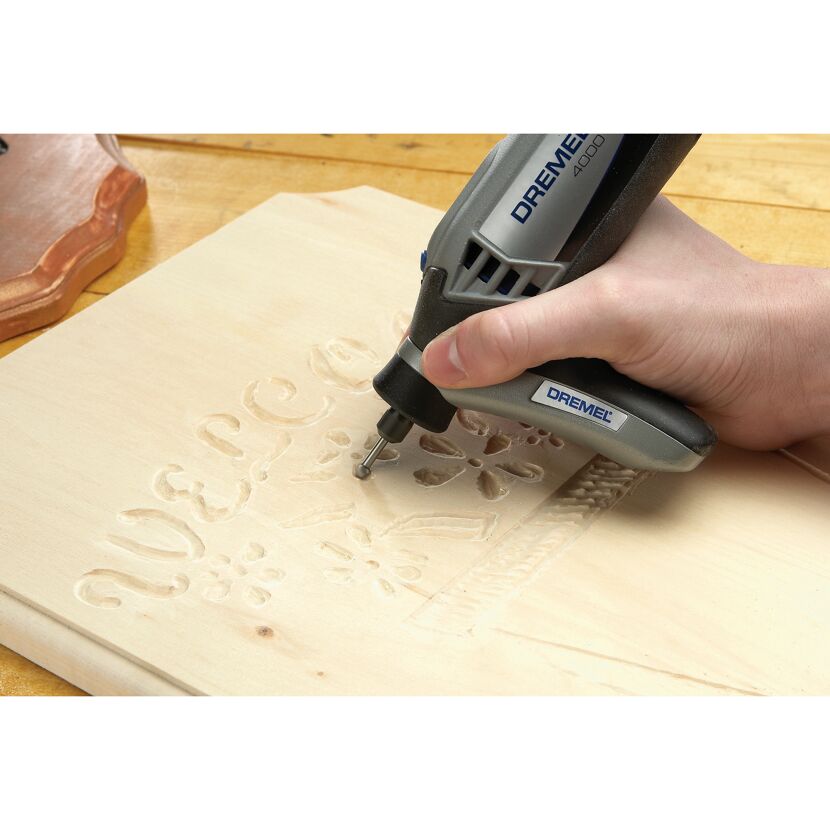 Person graviert mit einem Dremel 4000 ein Holzschild.