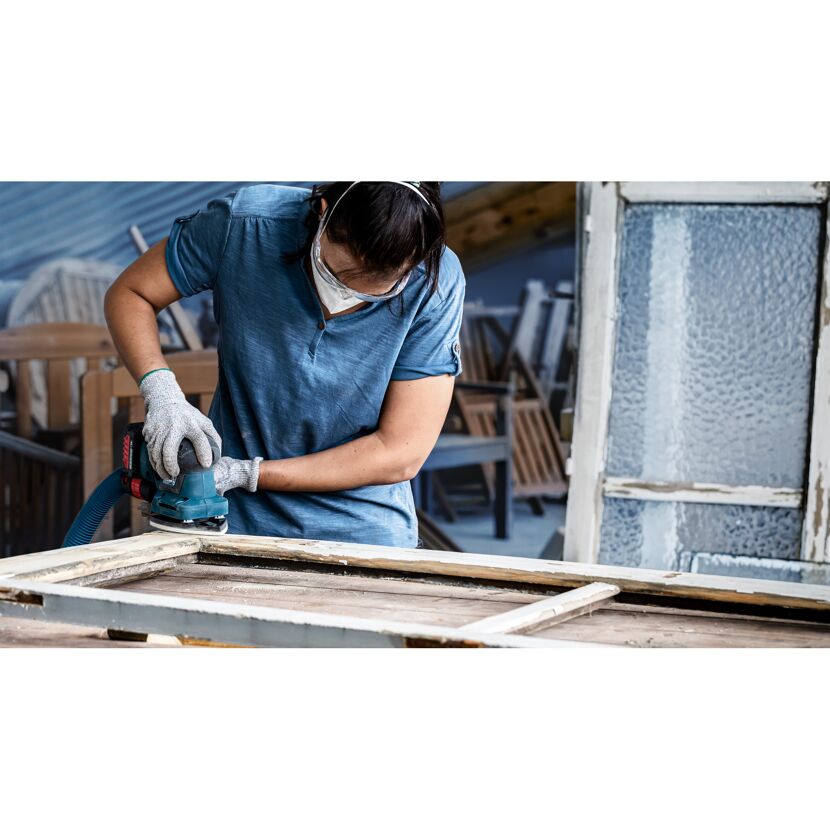 Person schleift einen Fensterrahmen mit einem Schwingschleifer.