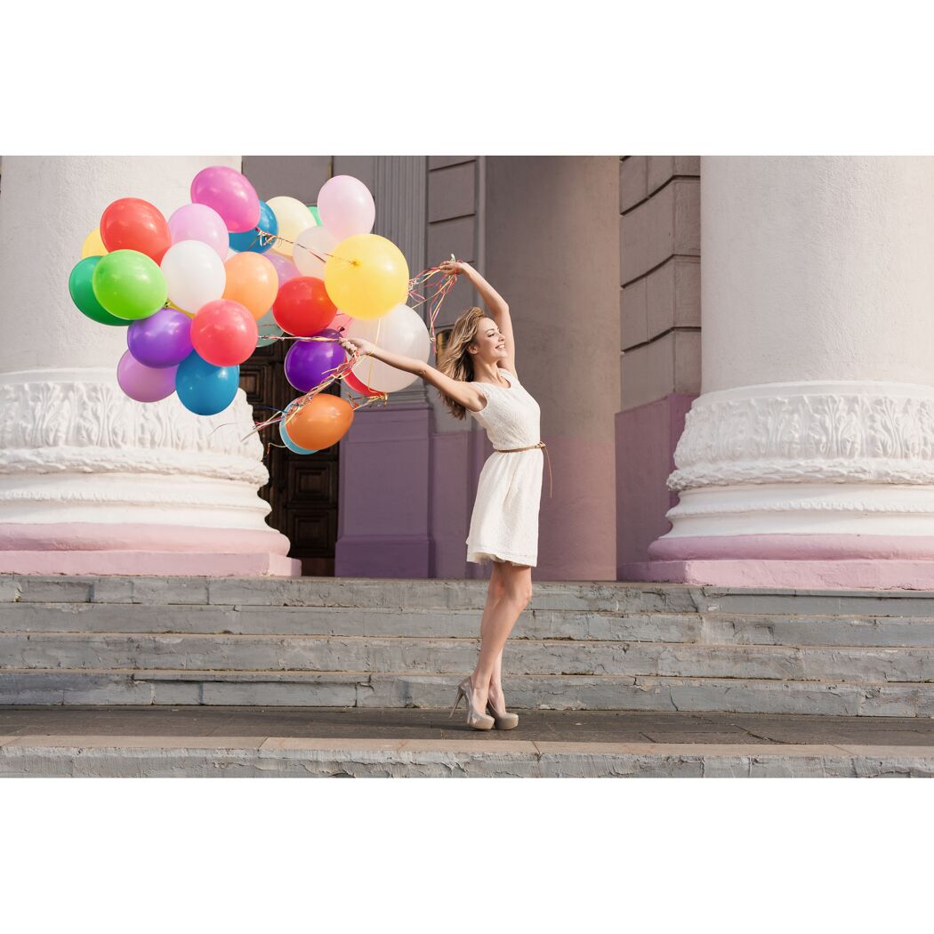 Person mit bunten Ballons vor Gebäude