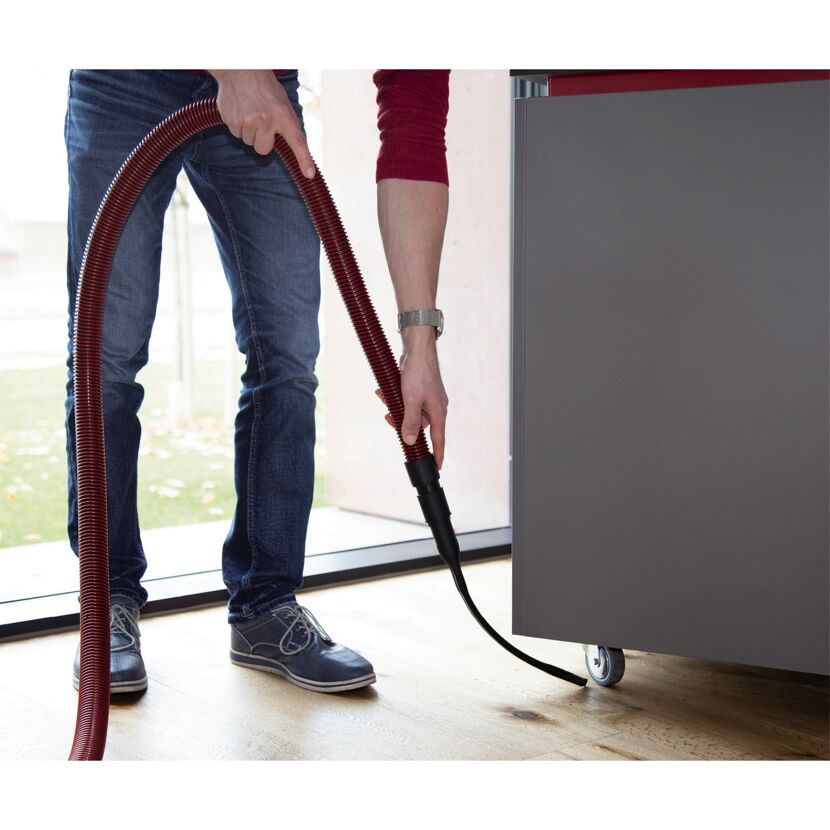 Person saugt unter einem Schrank