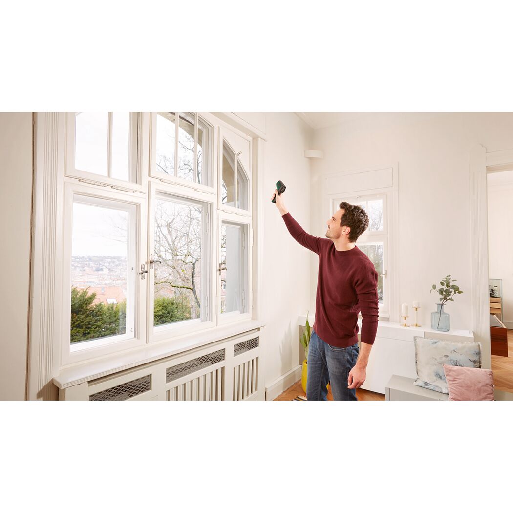 Person misst Temperatur eines Fensters mit Temperaturmessgerät