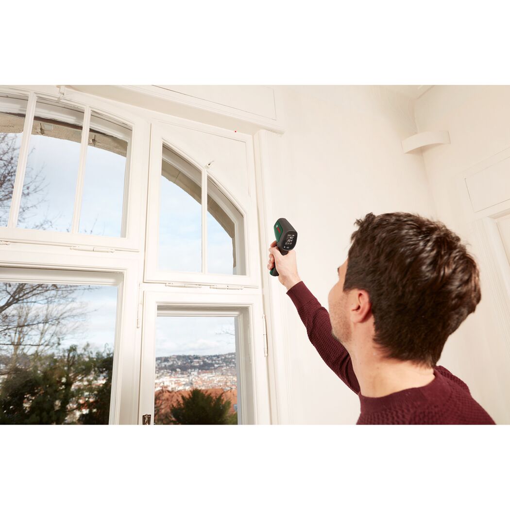 Person misst Temperatur an Fenster mit Bosch Temperaturmessgerät