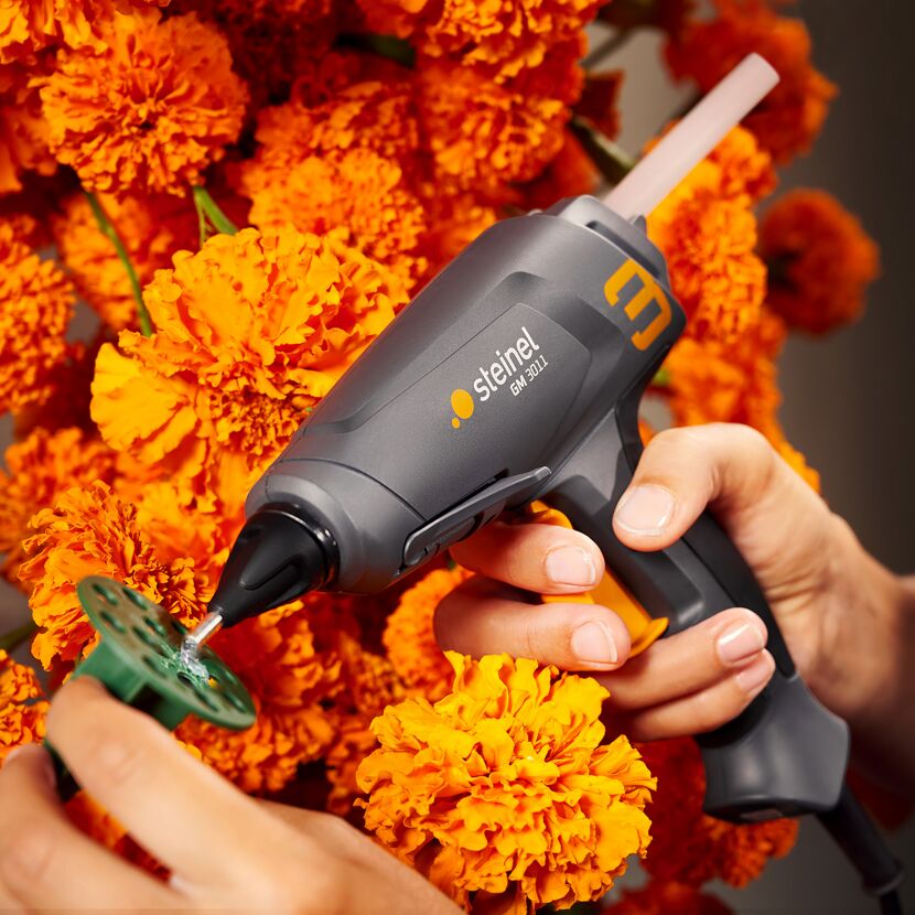 Heißklebepistole verklebt orangefarbene Blumen
