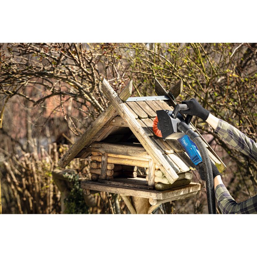 Person reinigt Vogelhaus mit Bürste