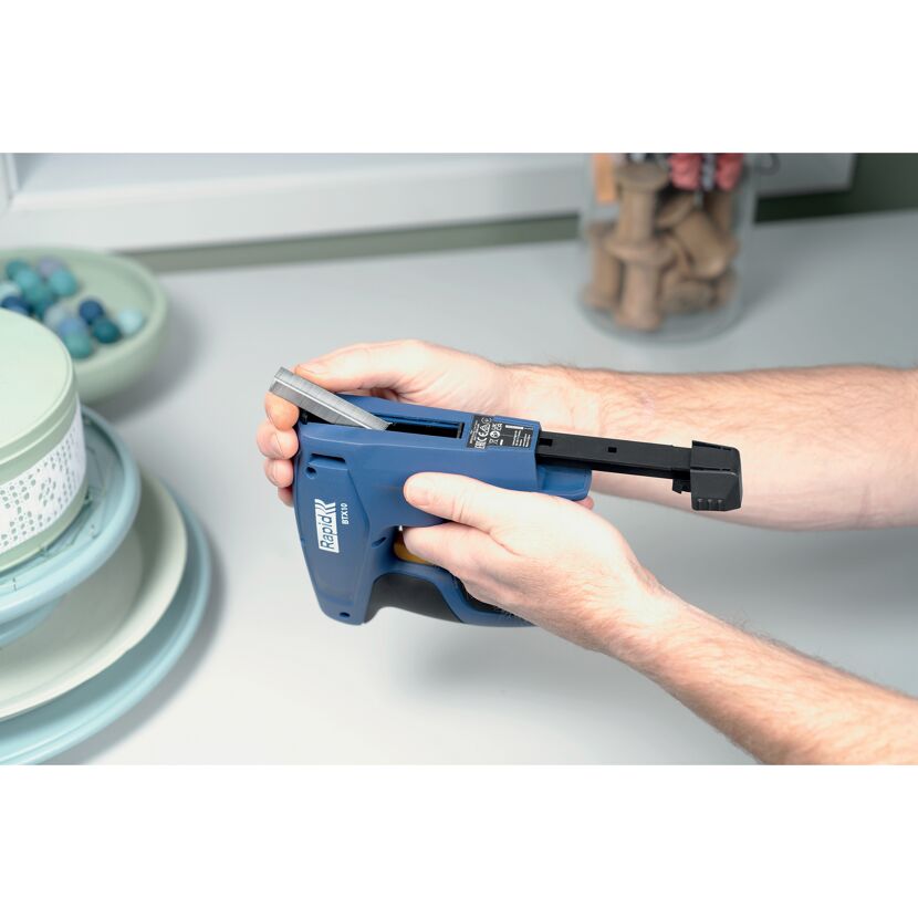 Person legt Klammern in einen blauen Tacker ein.