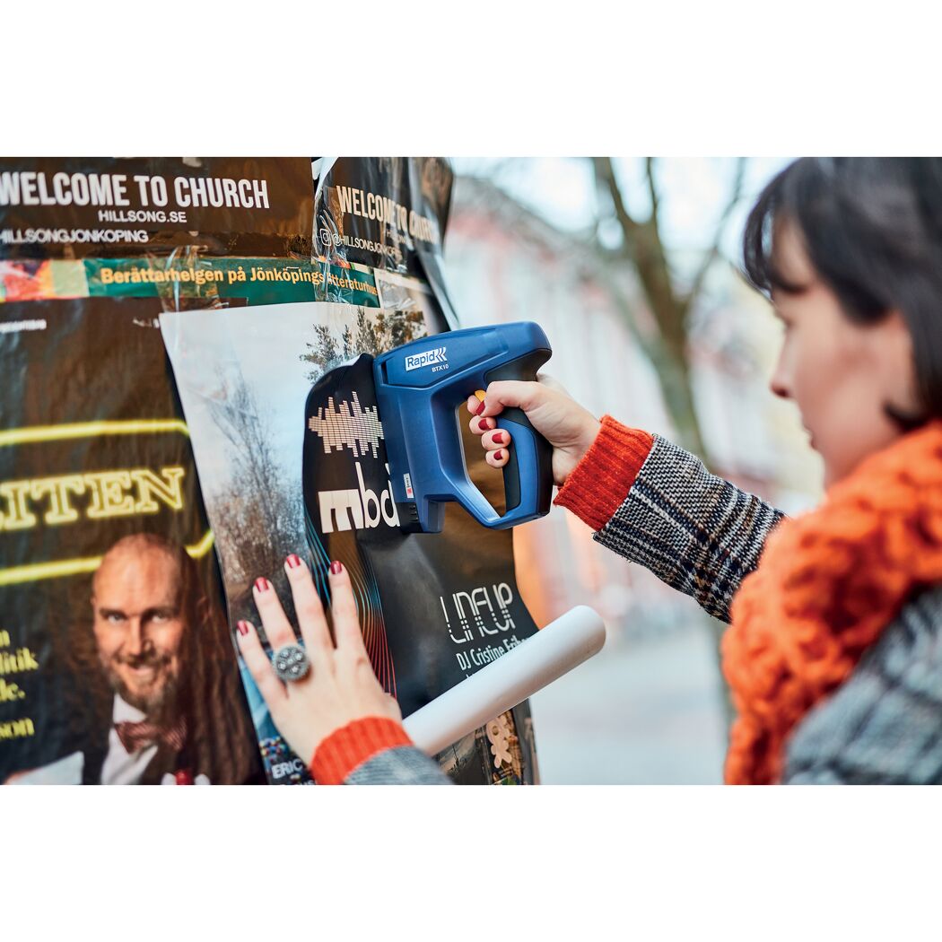 Person befestigt Poster mit einem Rapid BTX10 Tacker.