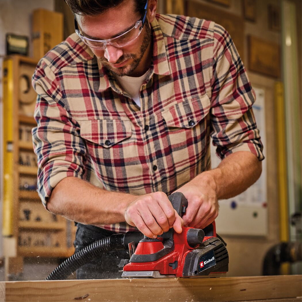 Person hobelt Holz mit Elektrohobel