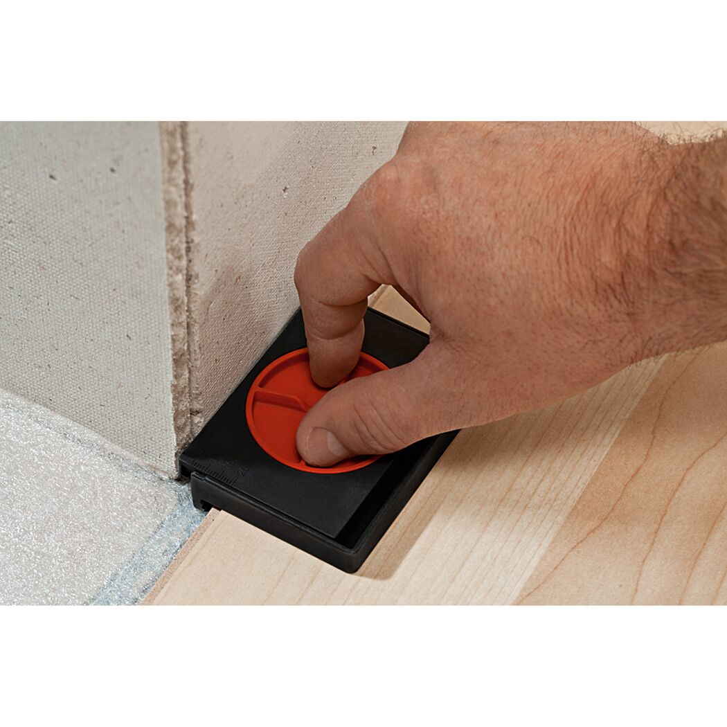 Person verwendet Abstandhalter beim Verlegen von Laminat.
