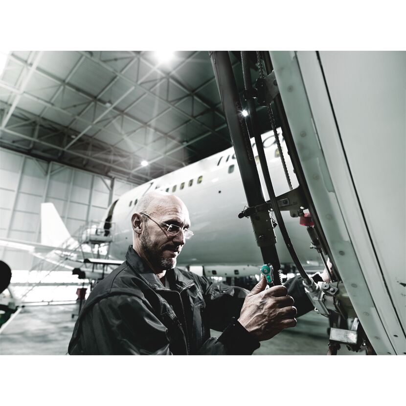 Person repariert ein Flugzeug mit einer Knarre.