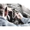 Person repariert ein Auto mit zwei Schraubenschlüsseln.