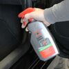 Person sprüht NIGRIN Geruchs-Entferner im Auto