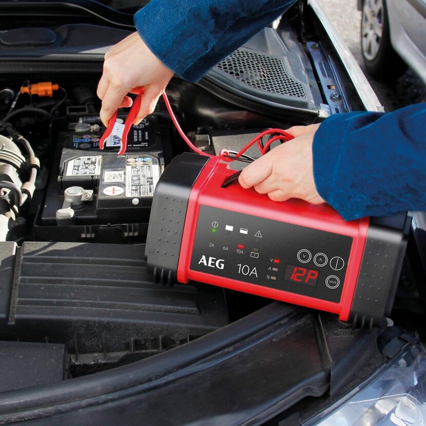 Person lädt Autobatterie mit Ladegerät