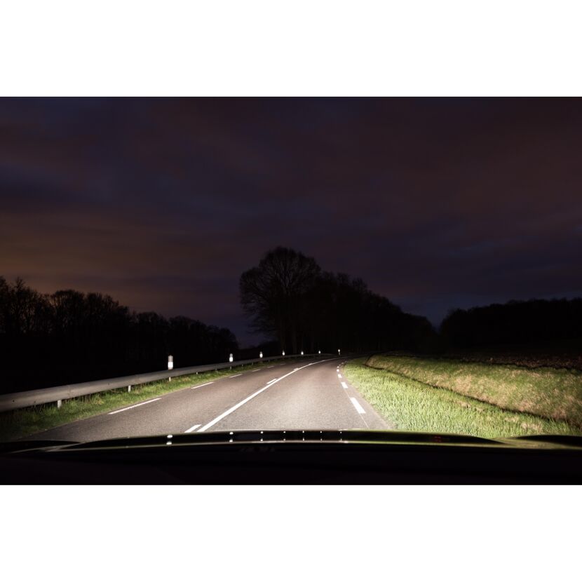 Scheinwerfer eines Autos leuchten die Straße in der Nacht aus.